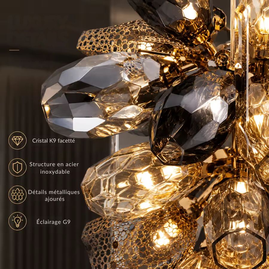 Détail du lustre sculptural en cristal K9 fumé, avec facettes brillantes, métal doré ajouré et éclairage G9 chaleureux.