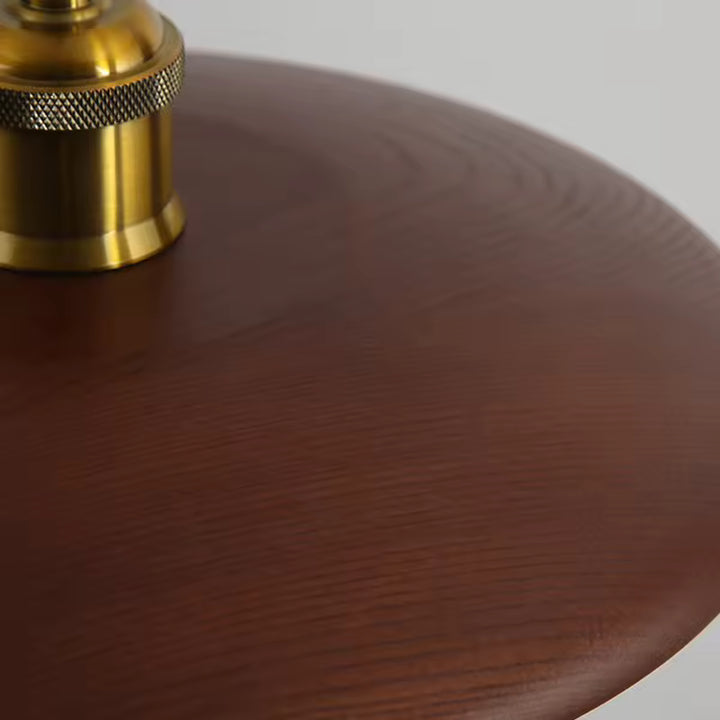 Gros plan sur le disque en bois foncé et la douille dorée, révélant un style japandi raffiné et chaleureux
