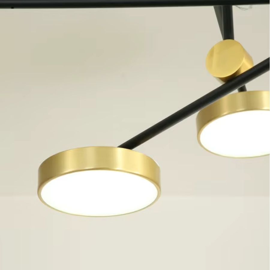Focus sur un disque LED doré relié à un bras noir, détail élégant d’un luminaire graphique au style contemporain.