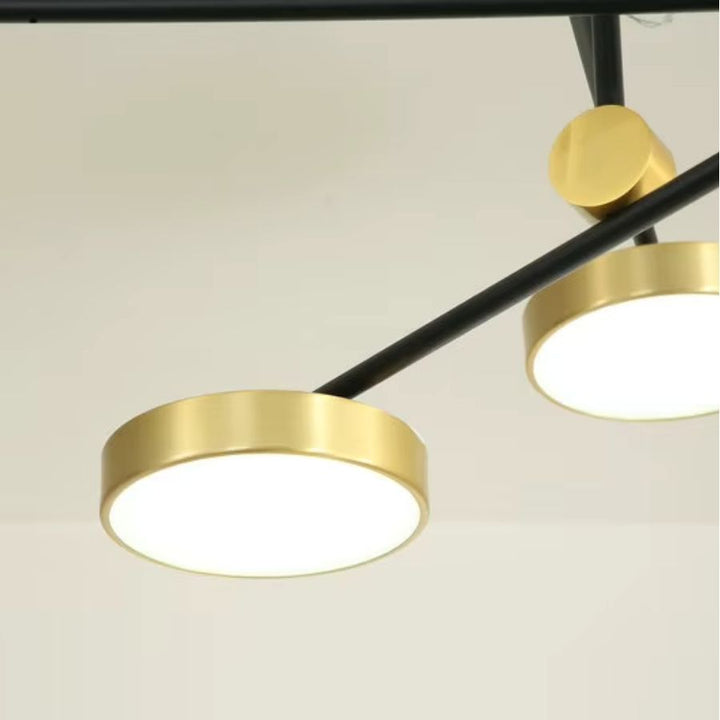 Focus sur un disque LED doré relié à un bras noir, détail élégant d’un luminaire graphique au style contemporain.