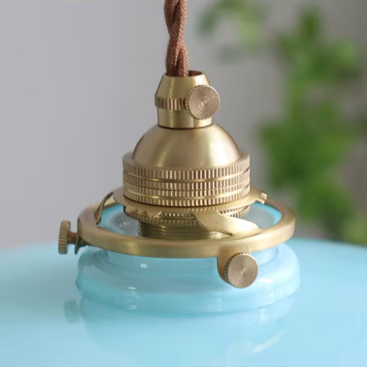 Gros plan sur la douille en laiton d’une suspension bleu pastel, au style rétro raffiné et délicatement vintage