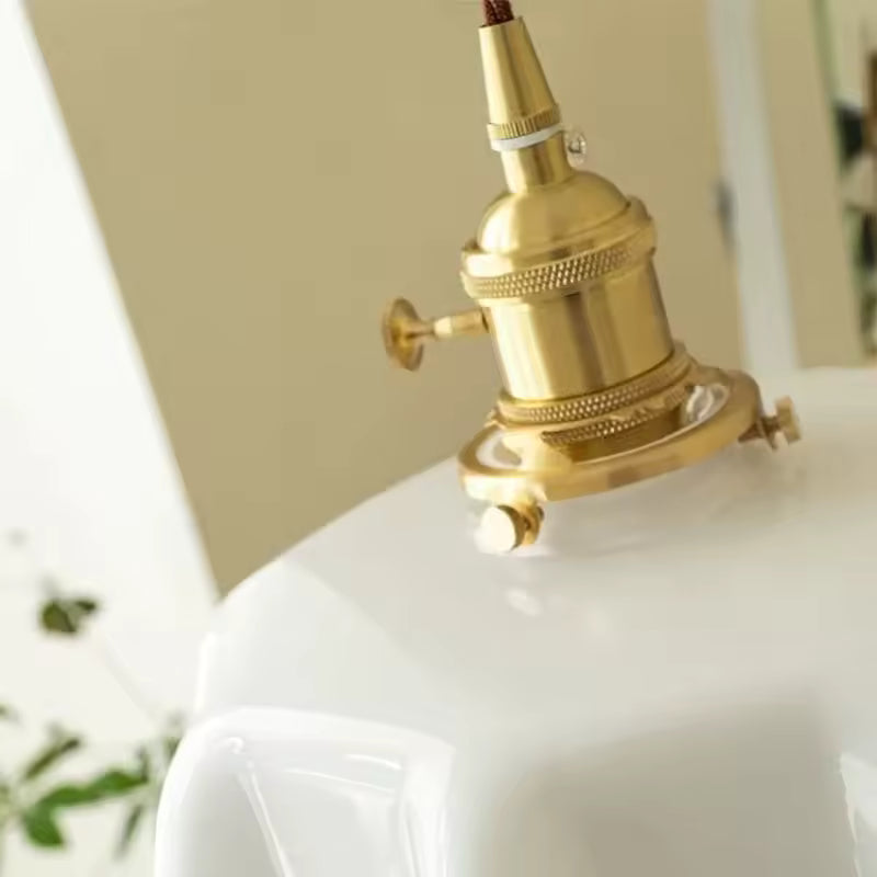 Gros plan sur la douille en laiton d’une suspension vintage à abat-jour festonné blanc au charme rétro