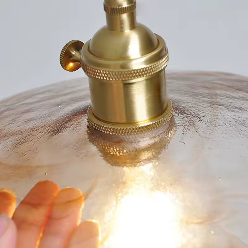 Gros plan sur la douille en laiton et la texture irrégulière du verre, aux finitions rétro et artisanales
