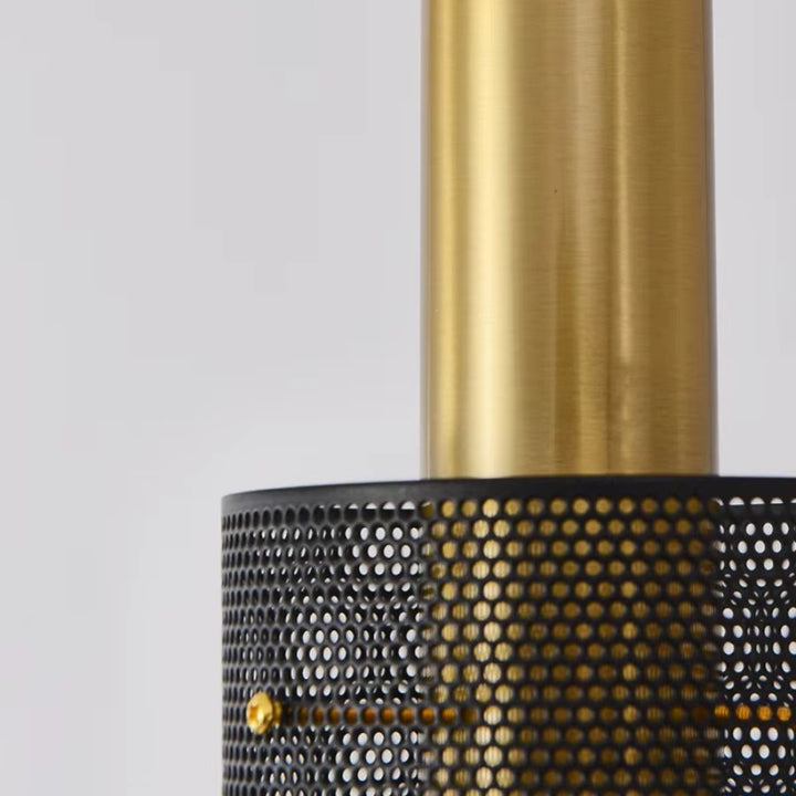 Détail de la finition dorée satinée et du métal ajouré noir de cette suspension cylindrique au design contemporain