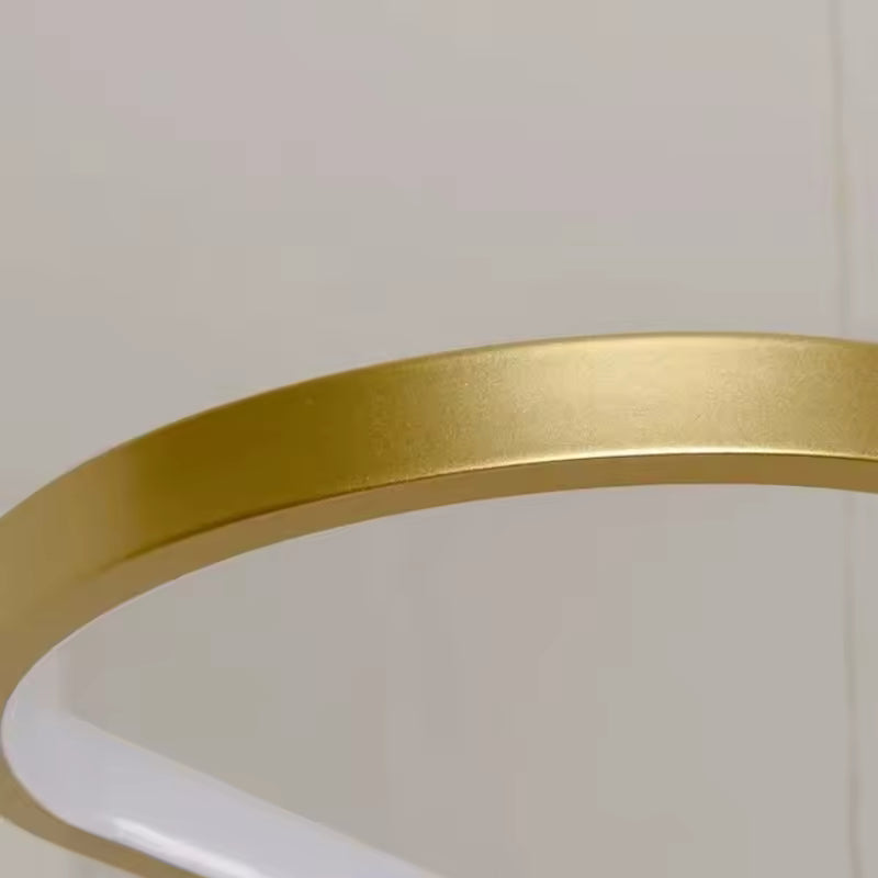 Détail de la finition dorée satinée et de la courbe arrondie de cette suspension LED au design épuré
