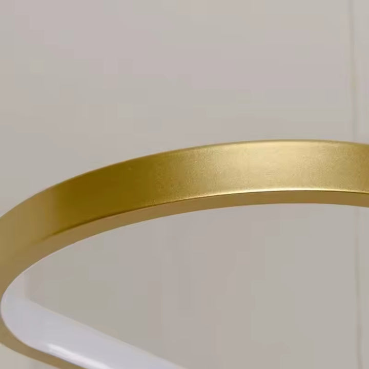 Détail de la finition dorée satinée et de la courbe arrondie de cette suspension LED au design épuré