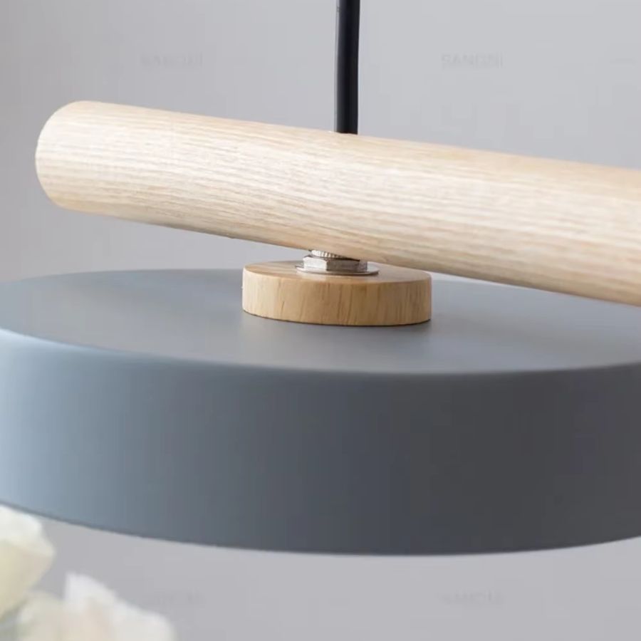 Détail de la fixation en bois reliant la barre claire au disque lumineux gris d’un luminaire scandinave