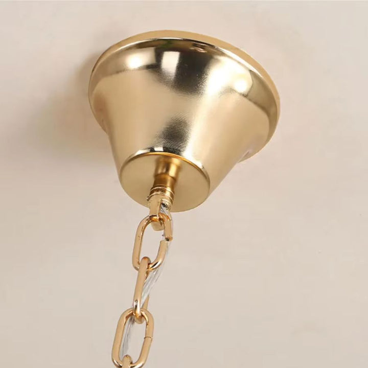Détail de la fixation dorée et de la chaîne du lustre en tiges de verre coloré au style élégant et contemporain