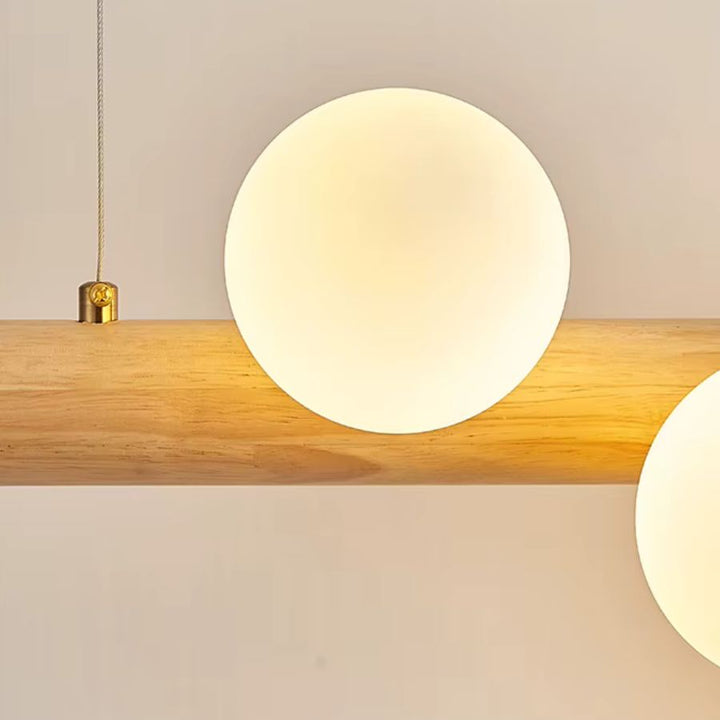 Détail d’un globe opalin posé sur une barre en bois clair, révélant le style naturel et minimaliste de la suspension.
