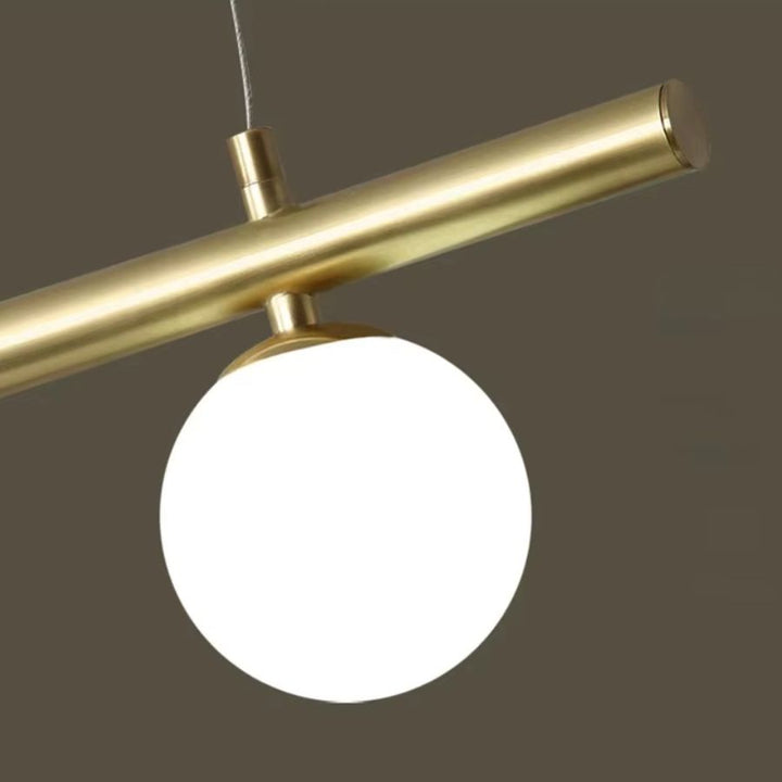 Gros plan sur un globe opalin fixé à une structure dorée tubulaire, au design géométrique sobre et raffiné