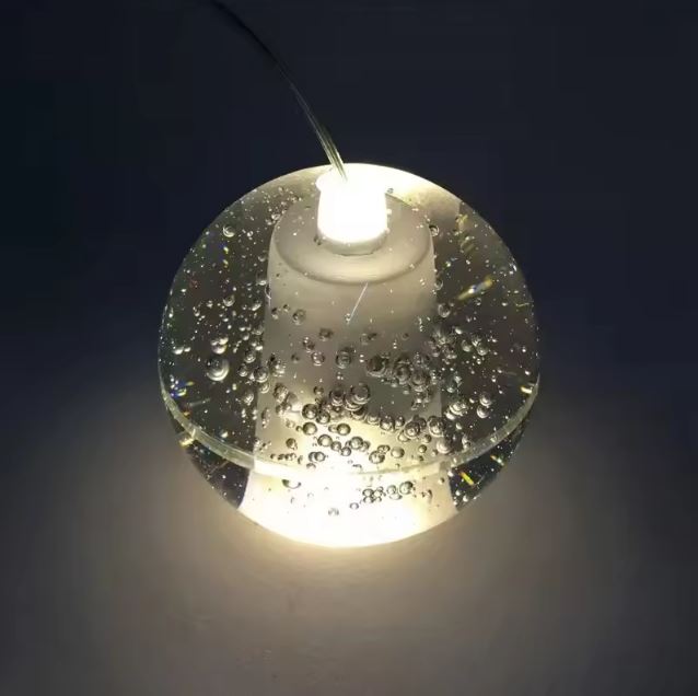 Détail de globe en verre bullé diffusant une lumière douce, suspension design contemporaine à l’effet cristal.