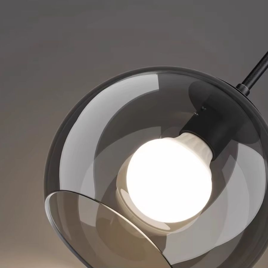 Gros plan sur un globe en verre fumé transparent révélant l’ampoule apparente et la finition noire du luminaire