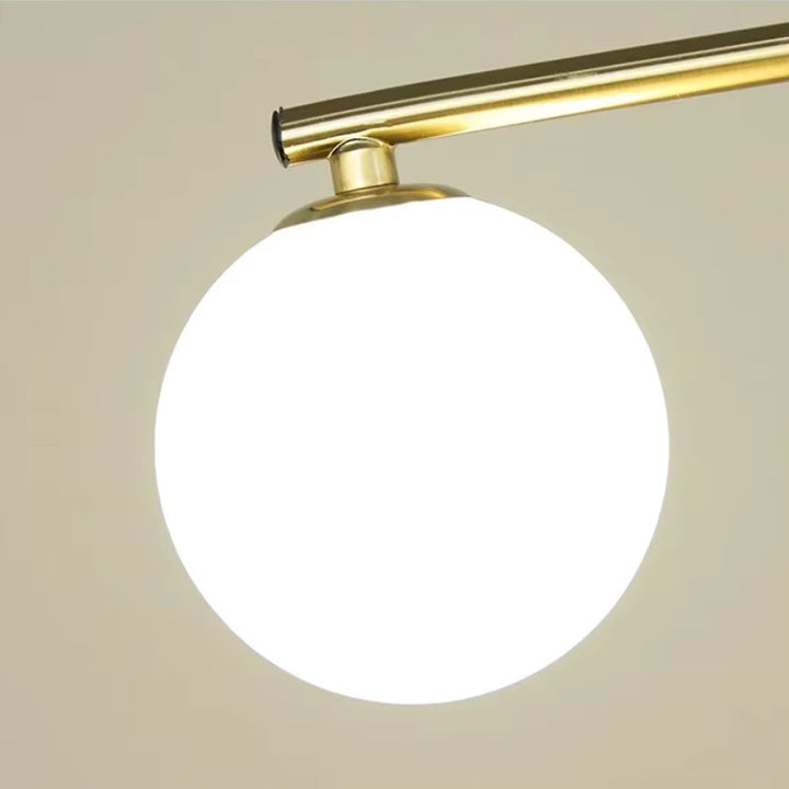 Sphère lumineuse en verre opalin blanc fixée à un bras métallique doré, détail raffiné d'un lustre contemporain.
