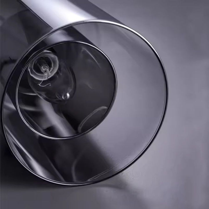Vue de dessous d'une suspension en verre fumé, révélant sa double paroi et son ampoule centrale au design moderne épuré.