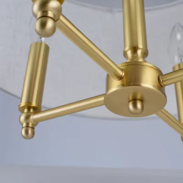 Gros plan sur les finitions en laiton doré de la suspension beige doré pour un design luxueux.