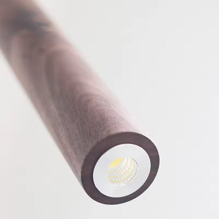 Gros plan sur la source LED d’une suspension cylindrique en bois foncé au design sobre et raffiné