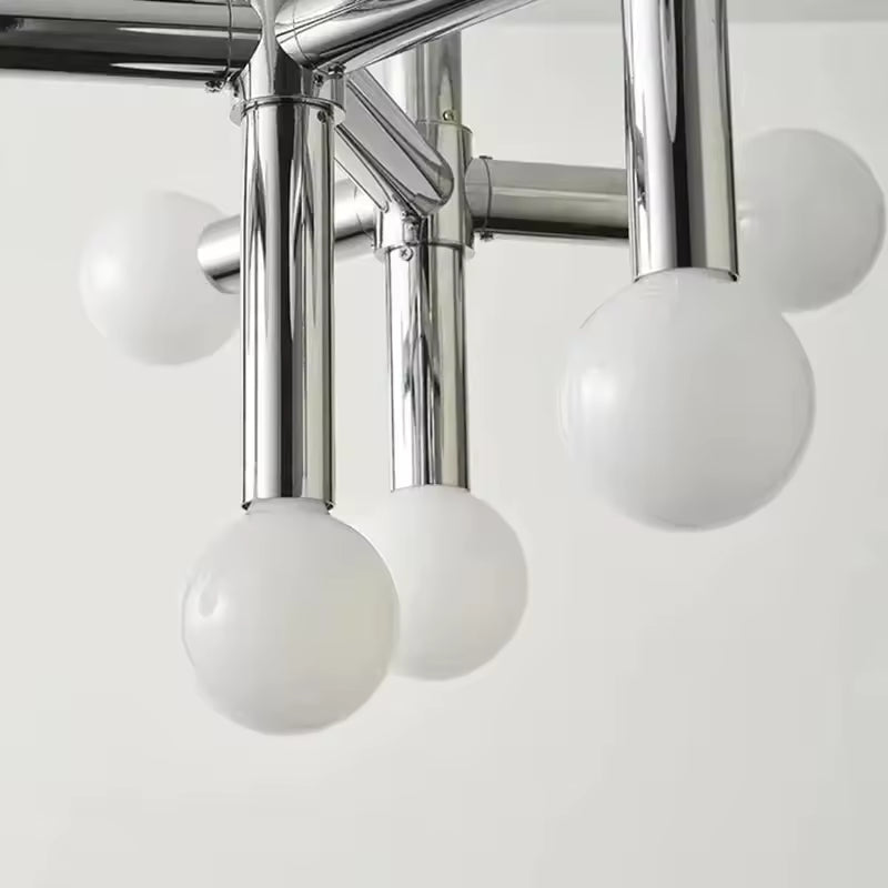 Gros plan sur les globes opalins et les tubes chromés d’un luminaire au design rétro-moderne raffiné