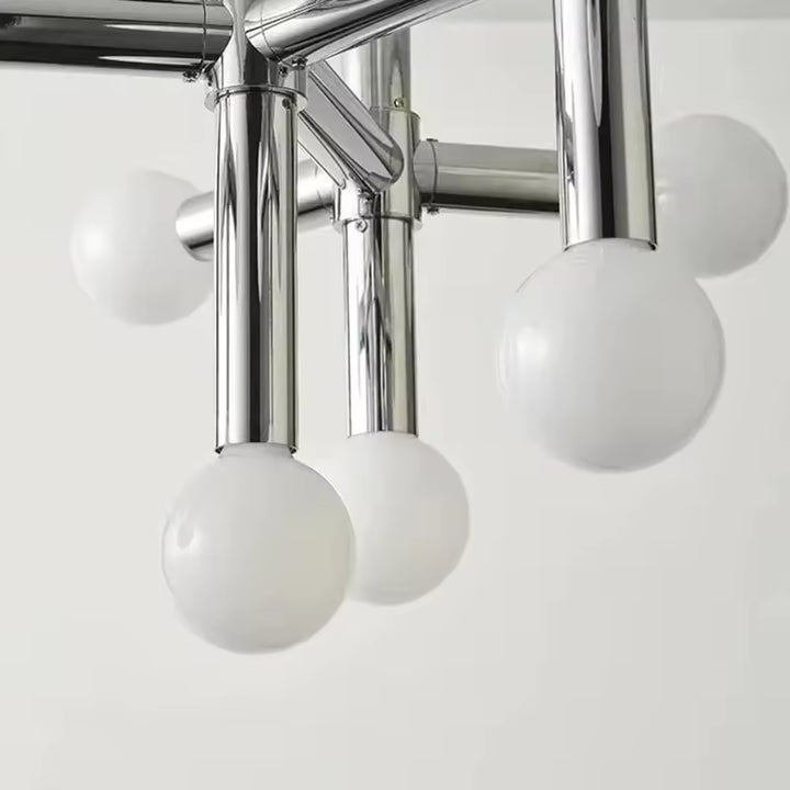 Gros plan sur les globes opalins et les tubes chromés d’un luminaire au design rétro-moderne raffiné