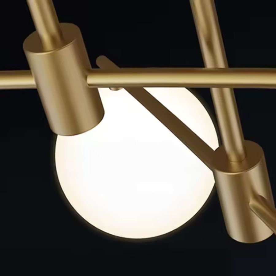 Gros plan sur les finitions dorées satinées et le globe en verre opalin d'un lustre design aux lignes géométriques.