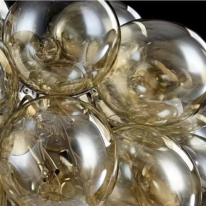 Gros plan sur les bulles en verre champagne d’un lustre grappe au rendu brillant, organique et sophistiqué