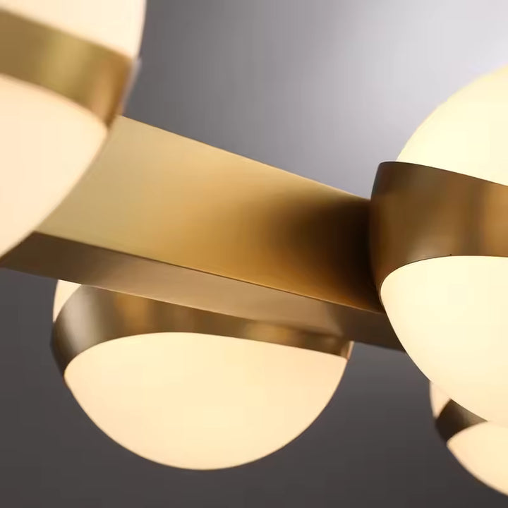 Gros plan sur les globes opalins cerclés de métal doré, révélant le style graphique et contemporain du lustre