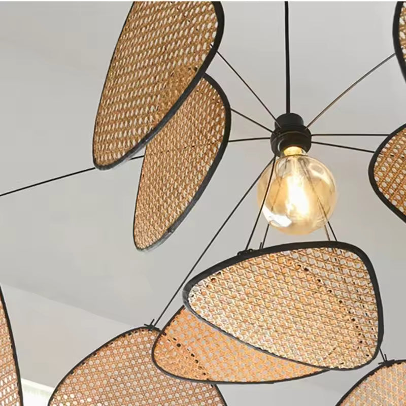 Détail du tressage autour de l’ampoule centrale, avec pétales ajourés en rotin et structure noire au style artisanal contemporain