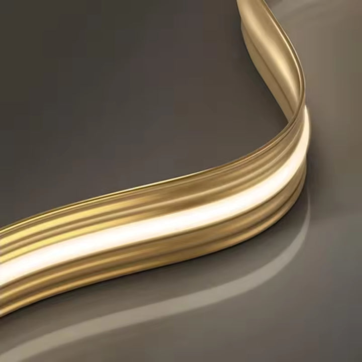 Vue rapprochée du lustre ruban LED révélant sa finition dorée, sa lumière intégrée et sa courbe fluide