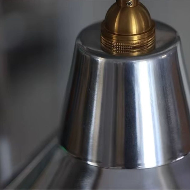 Gros plan sur la finition chromée et la douille couleur laiton d’une suspension industrielle au style rétro