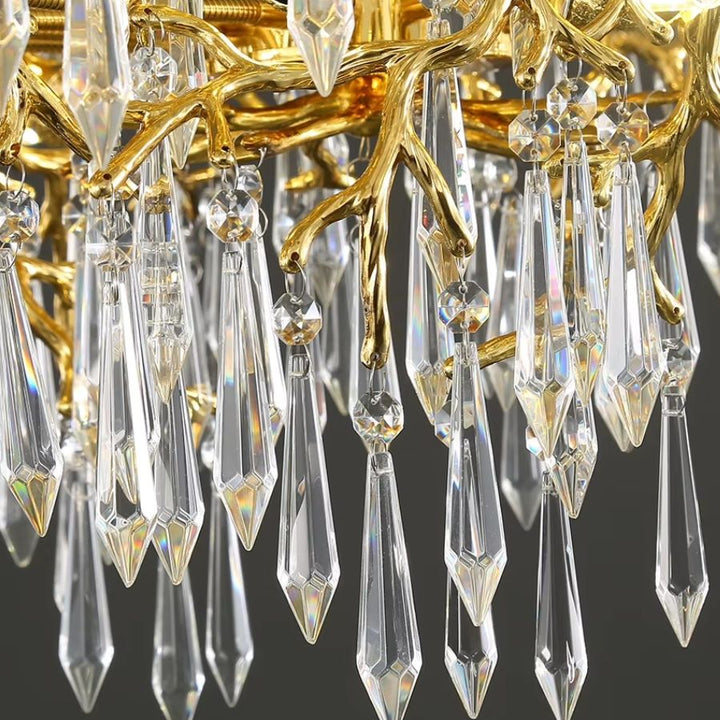 Gros plan sur les pampilles de cristal facettées suspendues aux branches dorées sculpturales du lustre