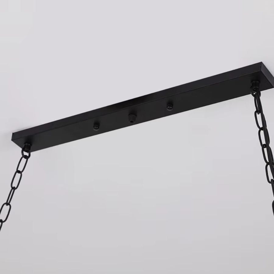 Détail du plafonnier noir et des chaînes métalliques d’une suspension en bois au style industriel et atelier