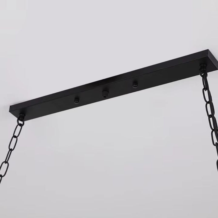 Détail du plafonnier noir et des chaînes métalliques d’une suspension en bois au style industriel et atelier