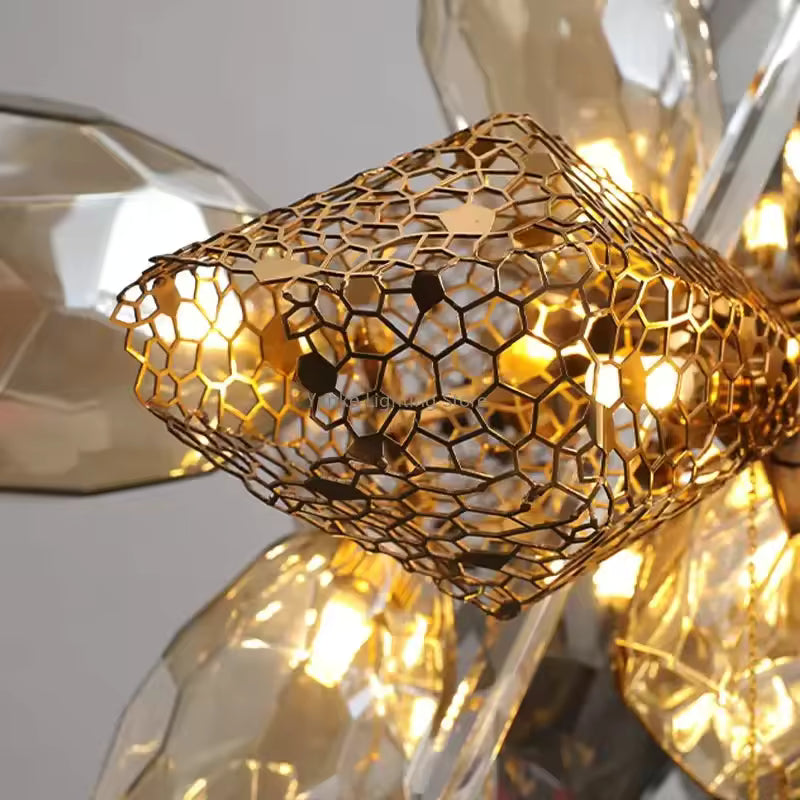 Gros plan sur la résille dorée ajourée du lustre en cristal fumé, avec lumière chaude et finition précieuse.