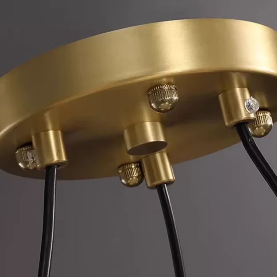 Détail de la rosace dorée et des câbles noirs du lustre orbital, dans un style moderne et sophistiqué