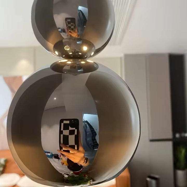 Gros plan sur les sphères chromées effet miroir d’une suspension sculpturale au design contemporain et futuriste