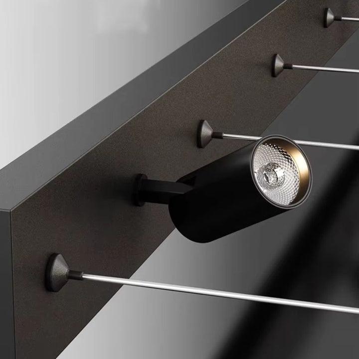 Gros plan sur un spot LED cylindrique noir orientable, intégré à la barre de fixation d'un lustre linéaire contemporain.