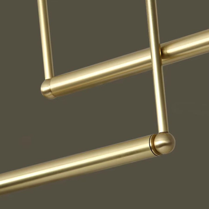 Détail de la structure tubulaire dorée et de ses raccords arrondis, soulignant le design géométrique du luminaire