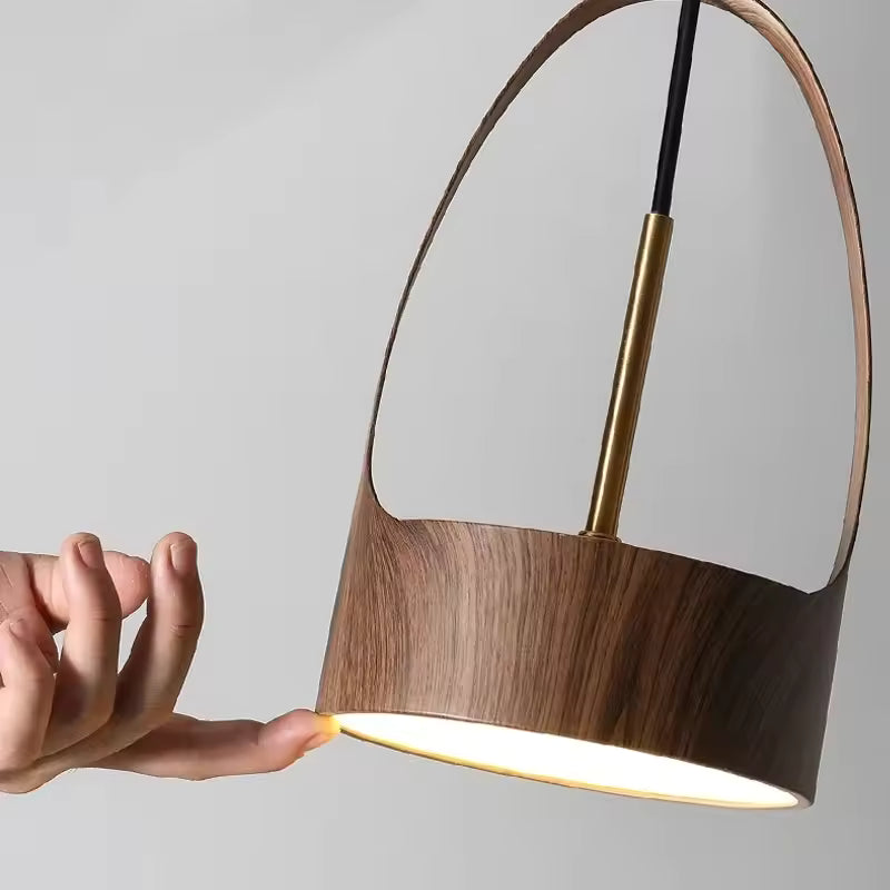 Gros plan sur l’arche métallique effet bois foncé et le diffuseur LED d’une suspension au design organique et raffiné