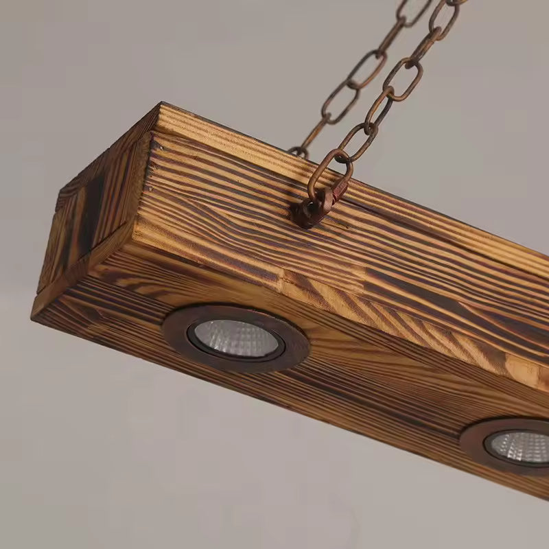 Gros plan sur la poutre en bois brûlé, ses spots encastrés et ses chaînes métalliques au style industriel