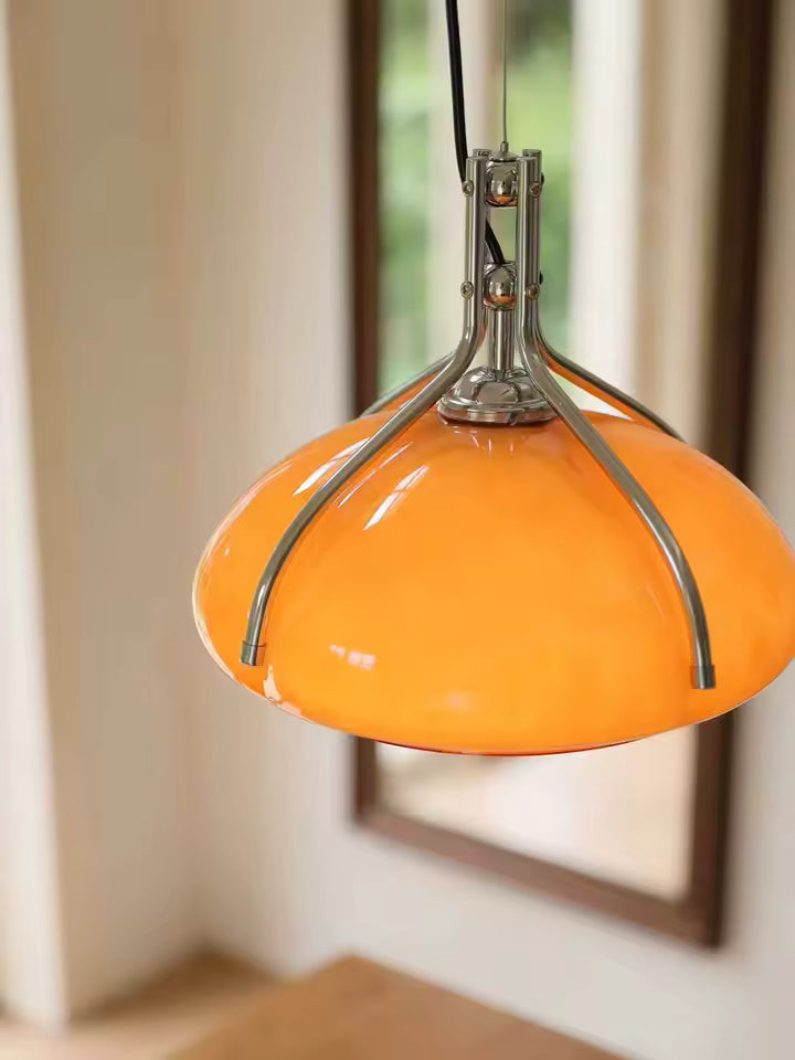 Gros plan sur une suspension dôme orange à armature chromée, au design Space Age rétro-futuriste