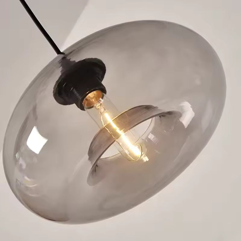 Vue en contre-plongée d’une suspension dôme en verre fumé, au design rétro et contemporain avec ampoule apparente