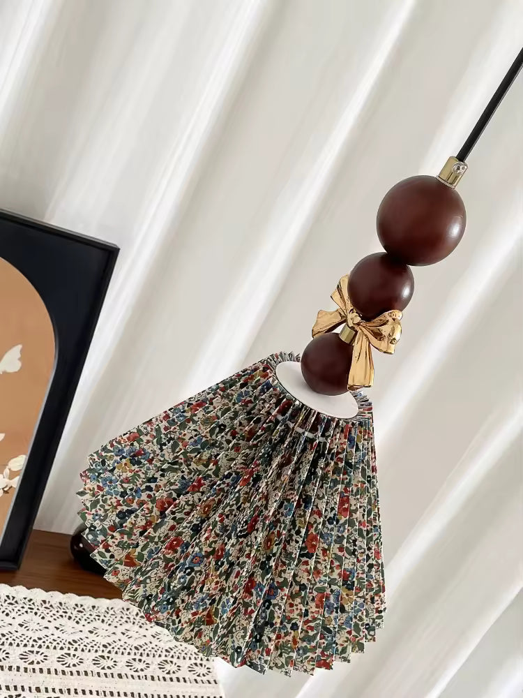 Vue inclinée de la suspension florale en tissu plissé, ornée de perles en bois brun et d’un nœud doré rétro