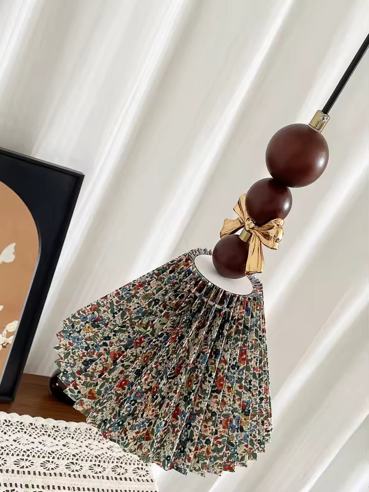 Vue inclinée de la suspension florale en tissu plissé, ornée de perles en bois brun et d’un nœud doré rétro