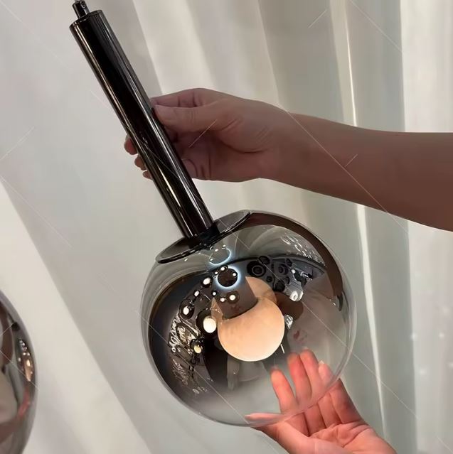 Détail de montage d’une suspension globe en verre fumé noir, finition design moderne et soignée.