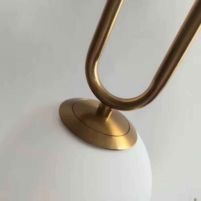 Détail suspension en laiton brossé avec globe en verre blanc, luminaire au design intemporel et finition élégante.