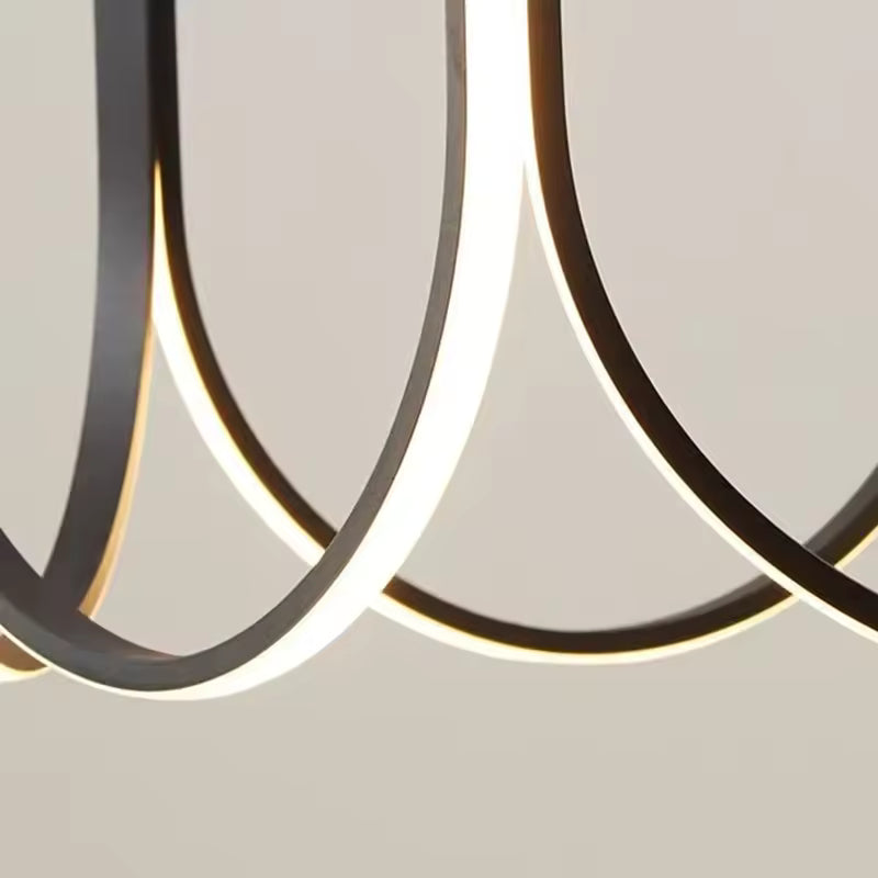 Gros plan sur les courbes LED d’une suspension noire au style sculptural, épuré et résolument moderne