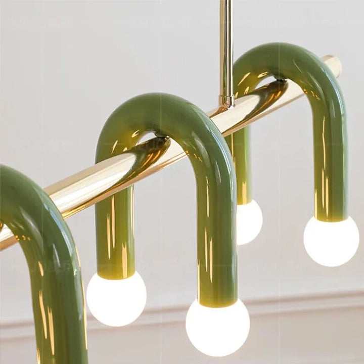 Zoom de détail sur les arches en laiton vert et les globes lumineux sphériques de la suspension haut de gamme.