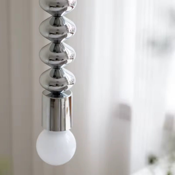 Détail du métal chromé sculptural et de l’ampoule globe, pour une suspension design au style contemporain