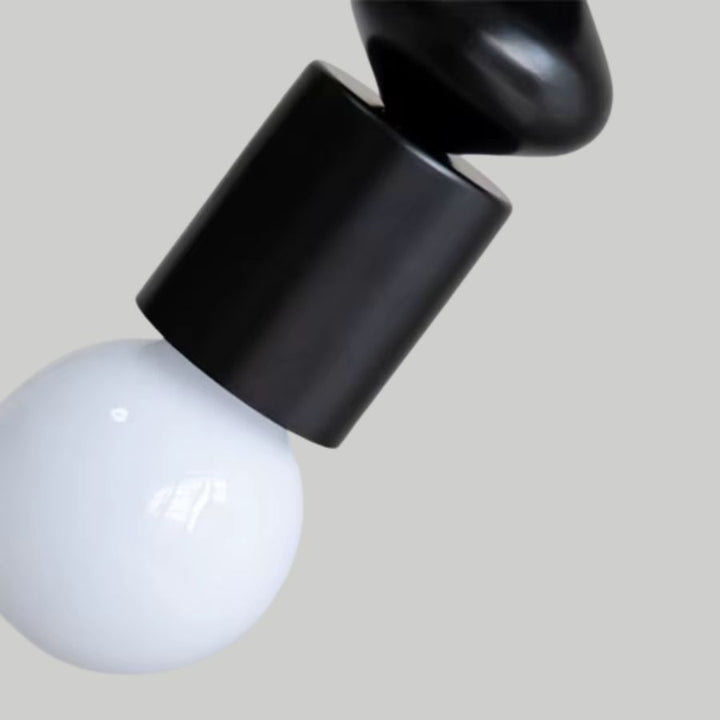 Gros plan sur le support noir et l’ampoule globe blanc d’une suspension totem au design sobre et contemporain