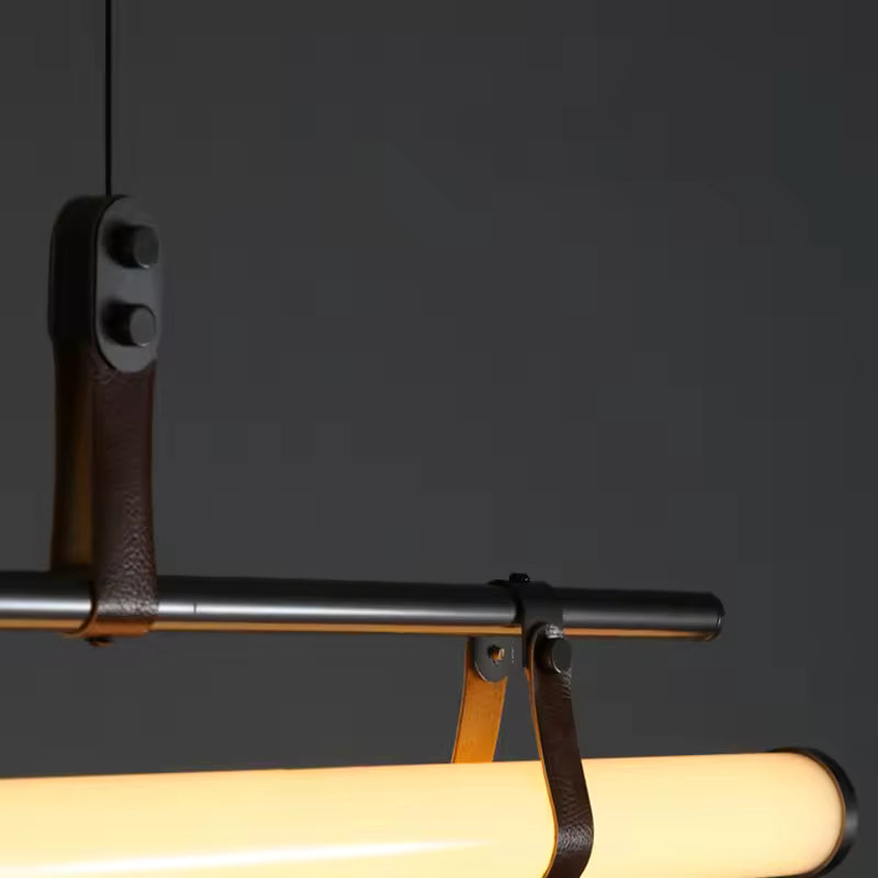 Gros plan sur les attaches en cuir et la structure noire d’une suspension avec tube LED au design contemporain