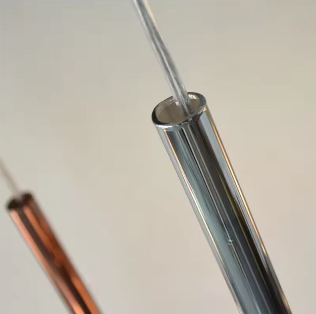 Détail de suspension tube en verre fumé gris et ambré, au style contemporain raffiné.